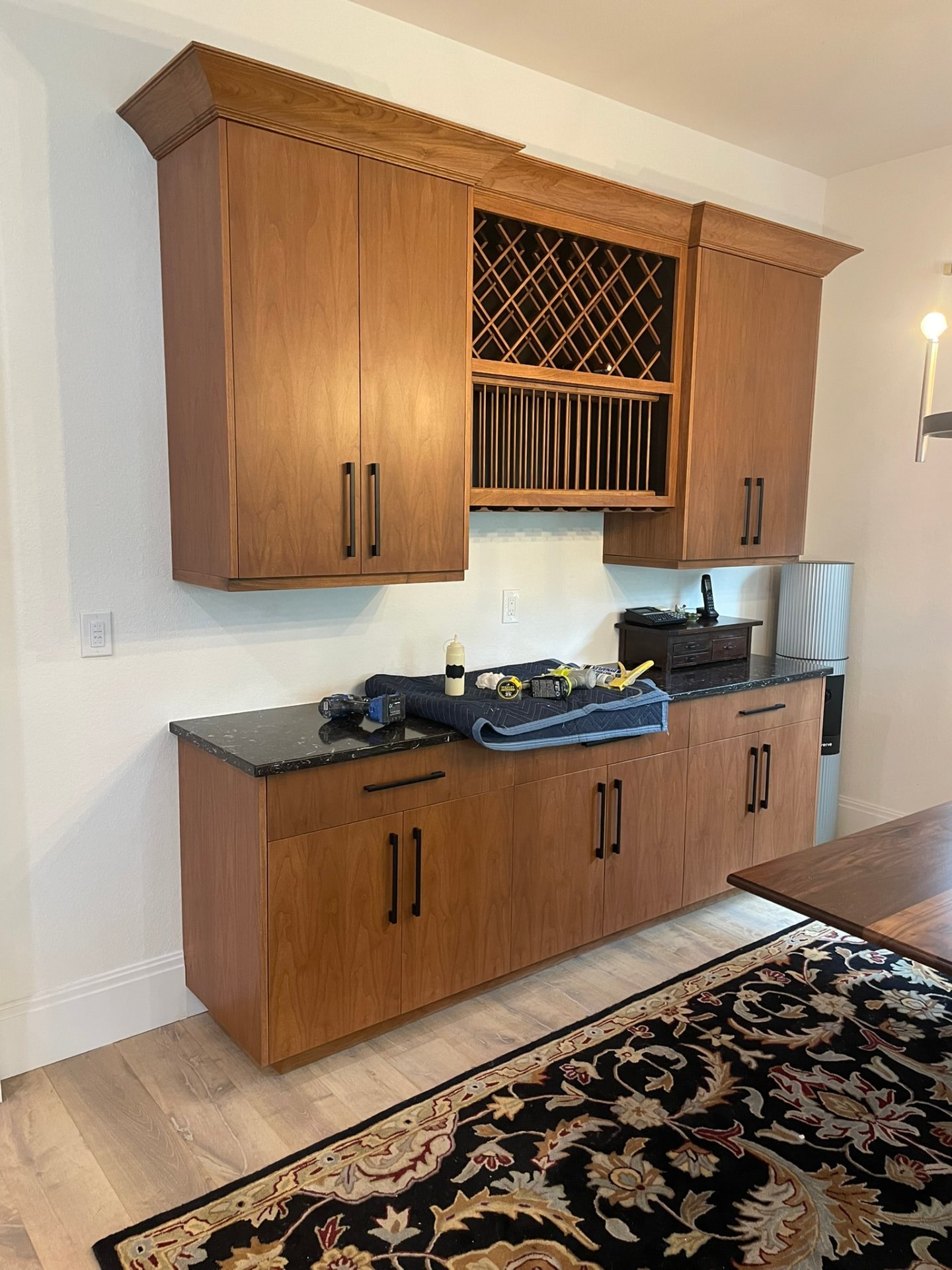 Custom stained cherry bar cabinetry with wine lattice, plate rack, and dark stone countertop