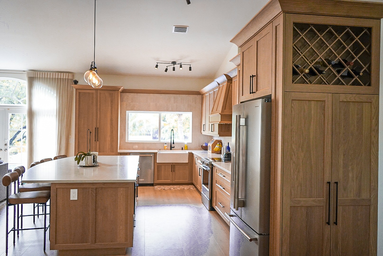 White oak refrigerator surround with wine lattice upper cabinet and stainless refrigerator