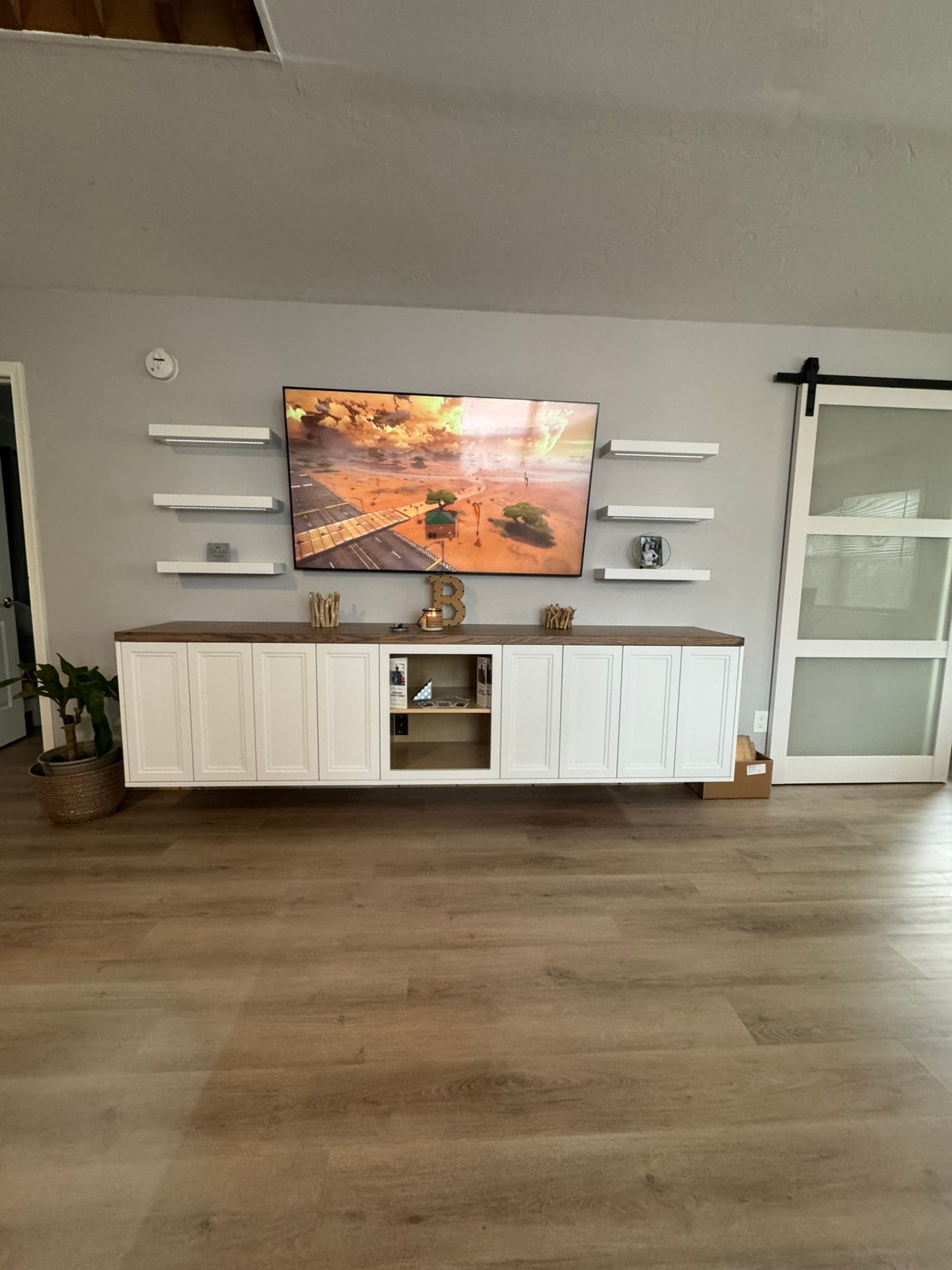 Custom floating white entertainment center with a stained wood top and white floating shelves