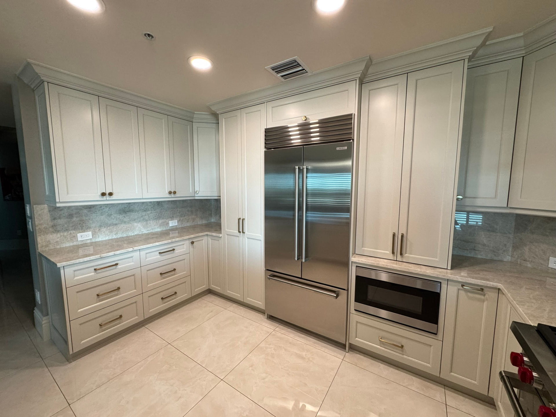 Corner run of painted kitchen cabinetry with drawer banks, upper cabinets, and stone backsplash