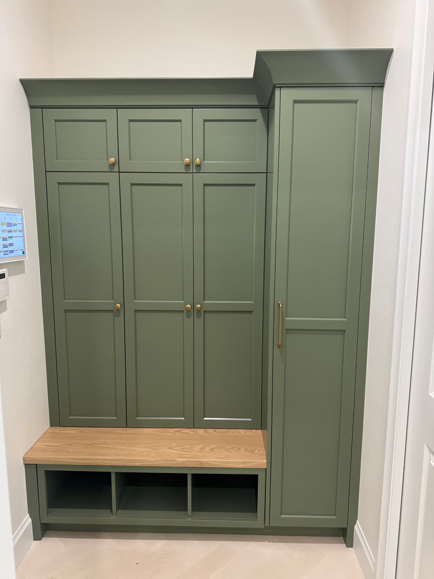 Mudroom entry with green painted lockers, oak bench seat, and open cubbies below