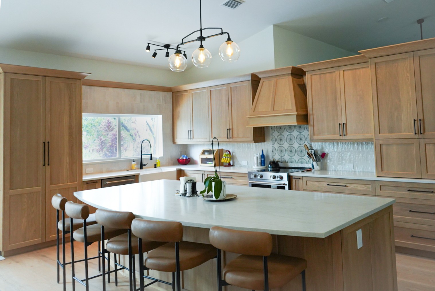White oak kitchen island with curved marble counter and leather counter stools
