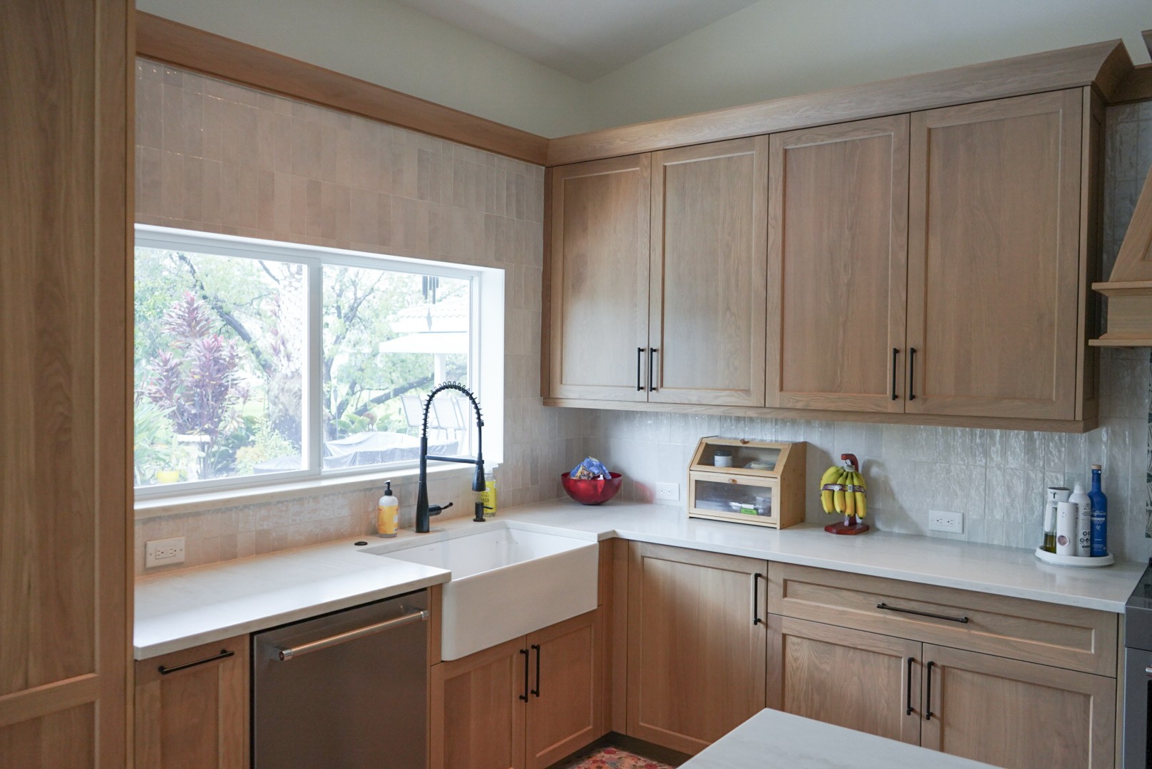 Custom white oak cabinetry with farmhouse sink, black faucet, and light quartz countertops