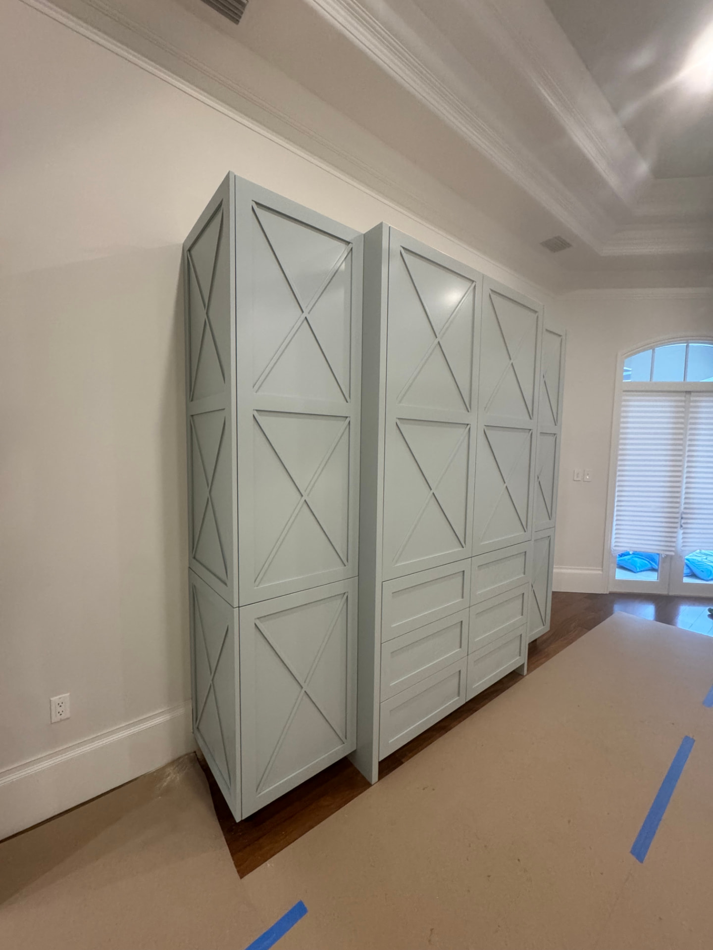 Angled view of the painted X-panel built-in cabinetry showing full-height doors and finished side panels