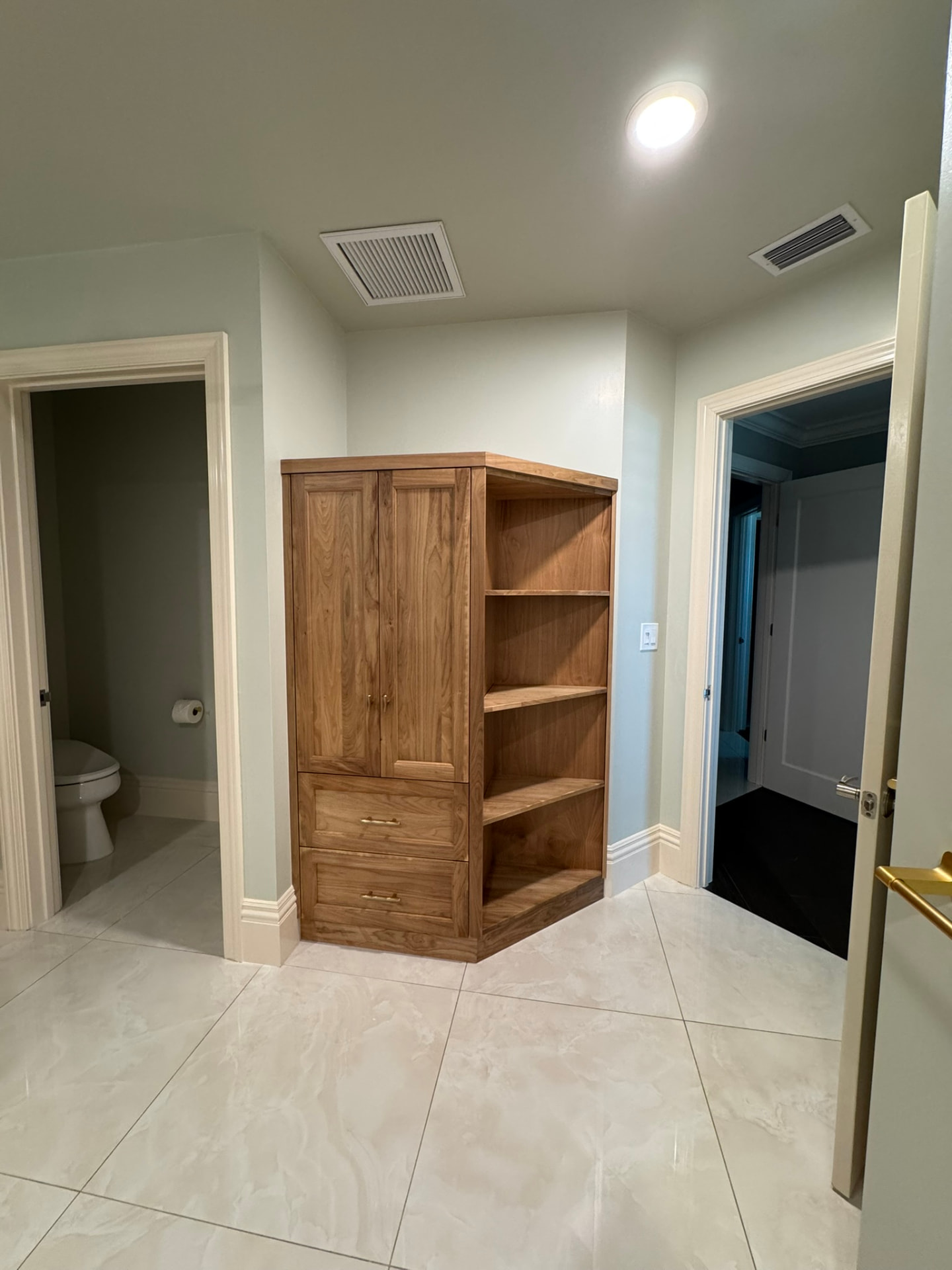 Walnut corner cabinet installed in the bathroom entry between doorways