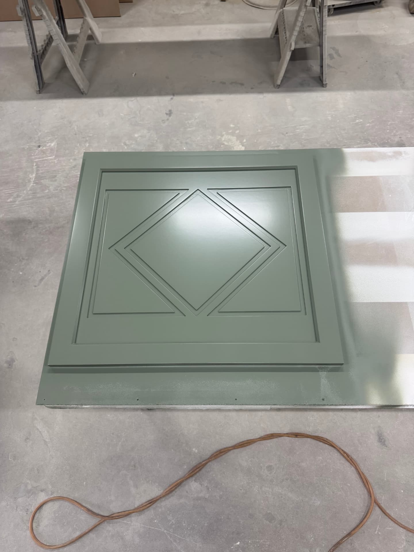 Sage green painted cabinet door with a diamond applied-molding detail after spraying