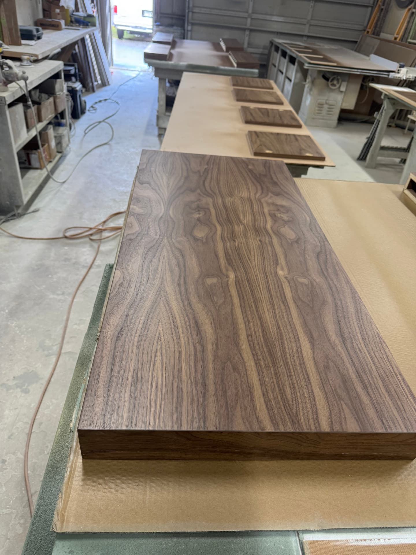 Clear-coated walnut floating shelf with matched grain drying in the shop