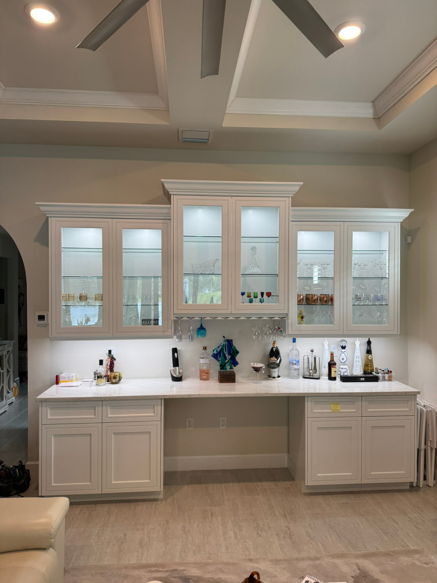 Painted bar cabinetry with stemware racks, glassware display, and flanking base cabinets
