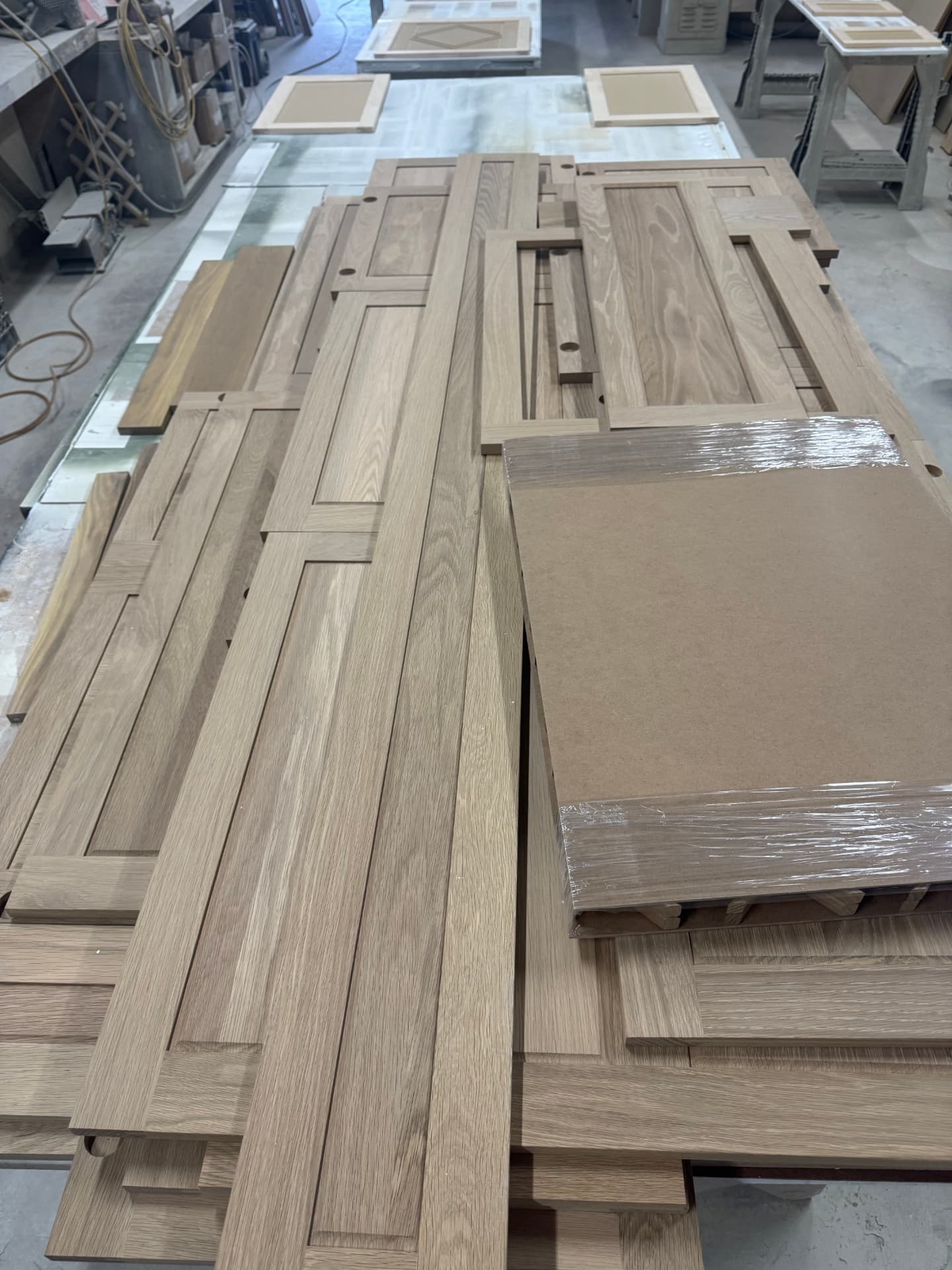 Stacks of white oak cabinet doors and panels prepped for finishing in the shop