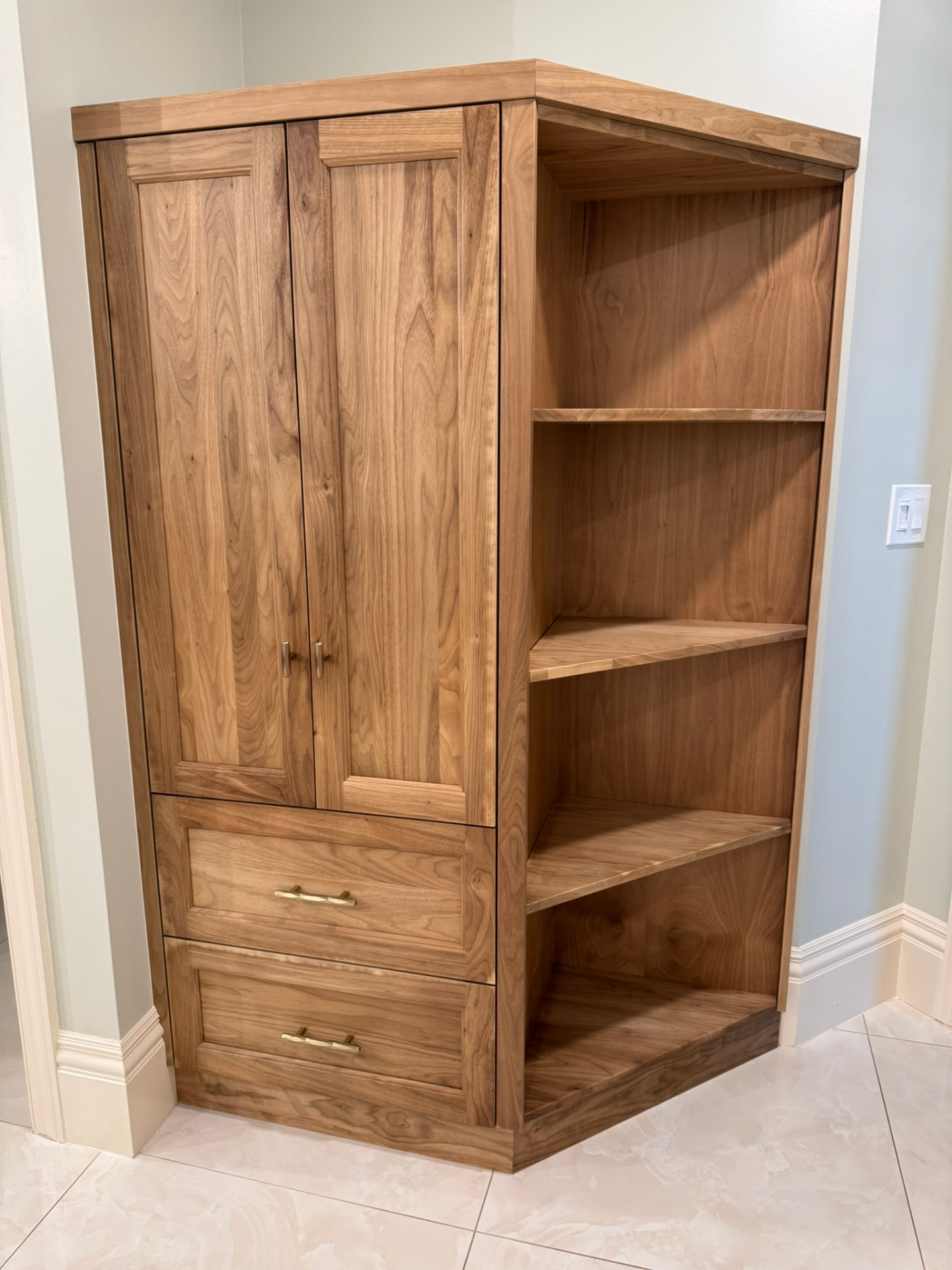 Custom walnut corner storage cabinet with paneled doors, two drawers, and open shelving