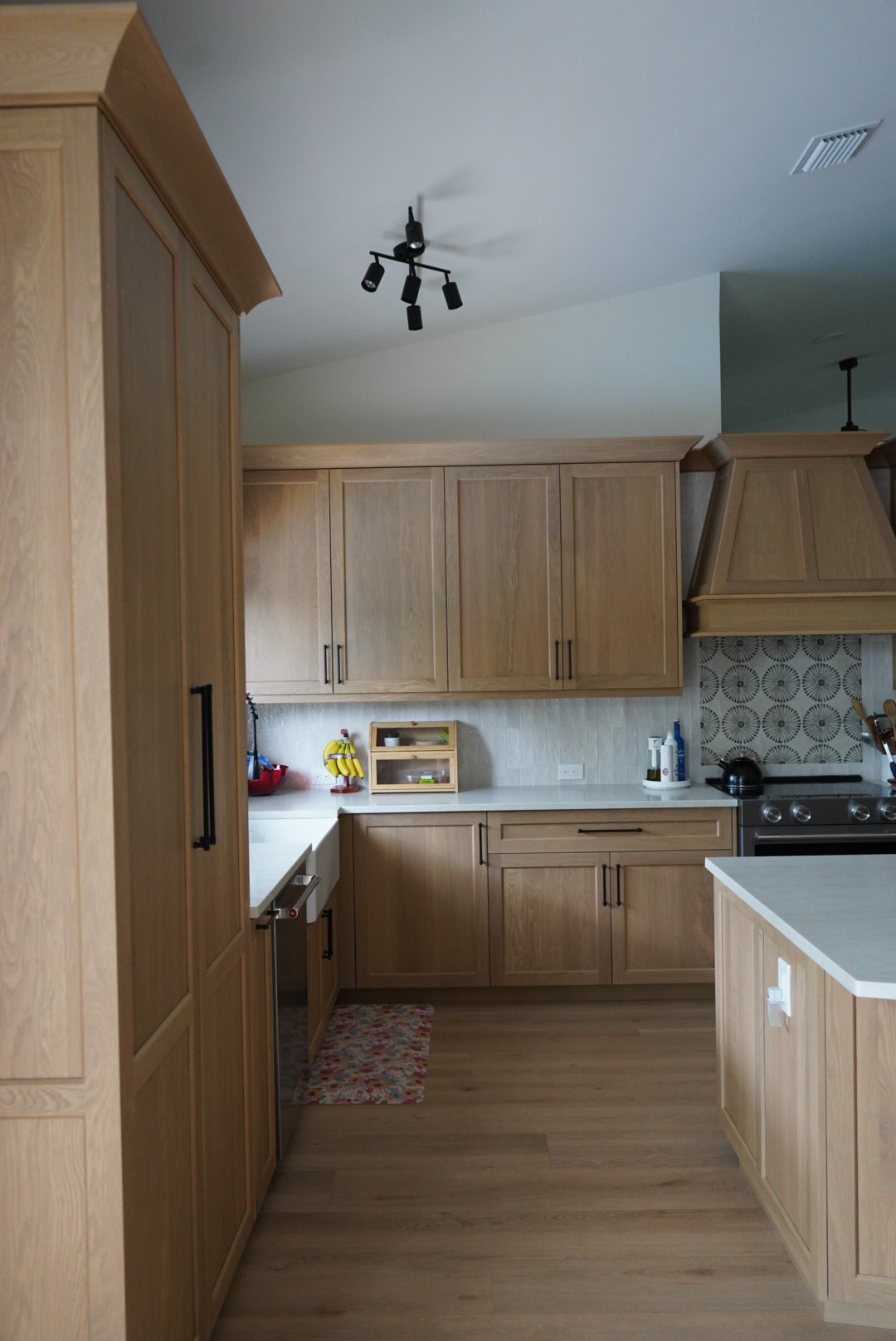 Overhead angled view of the white oak kitchen showing the hood, island, and full cabinet run