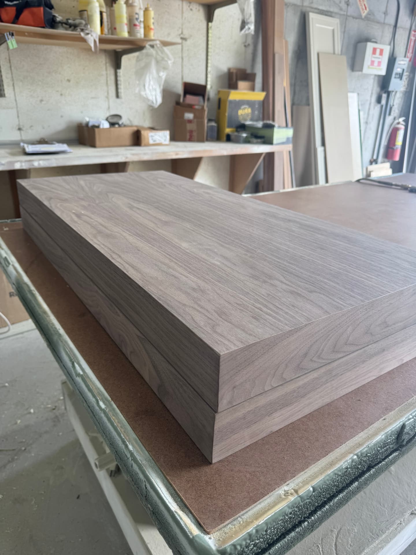 Stacked walnut floating shelves with mitered edges after clear coating