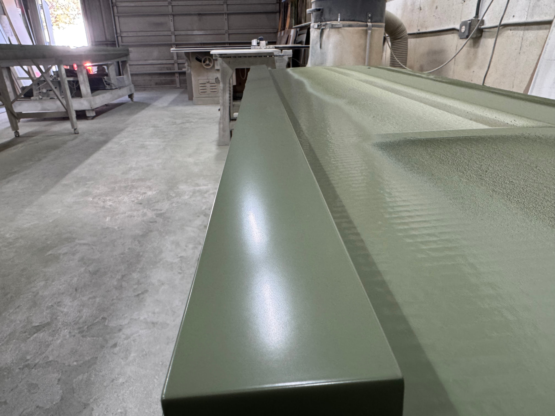 Freshly sprayed sage green cabinet doors and panels curing in the finishing shop