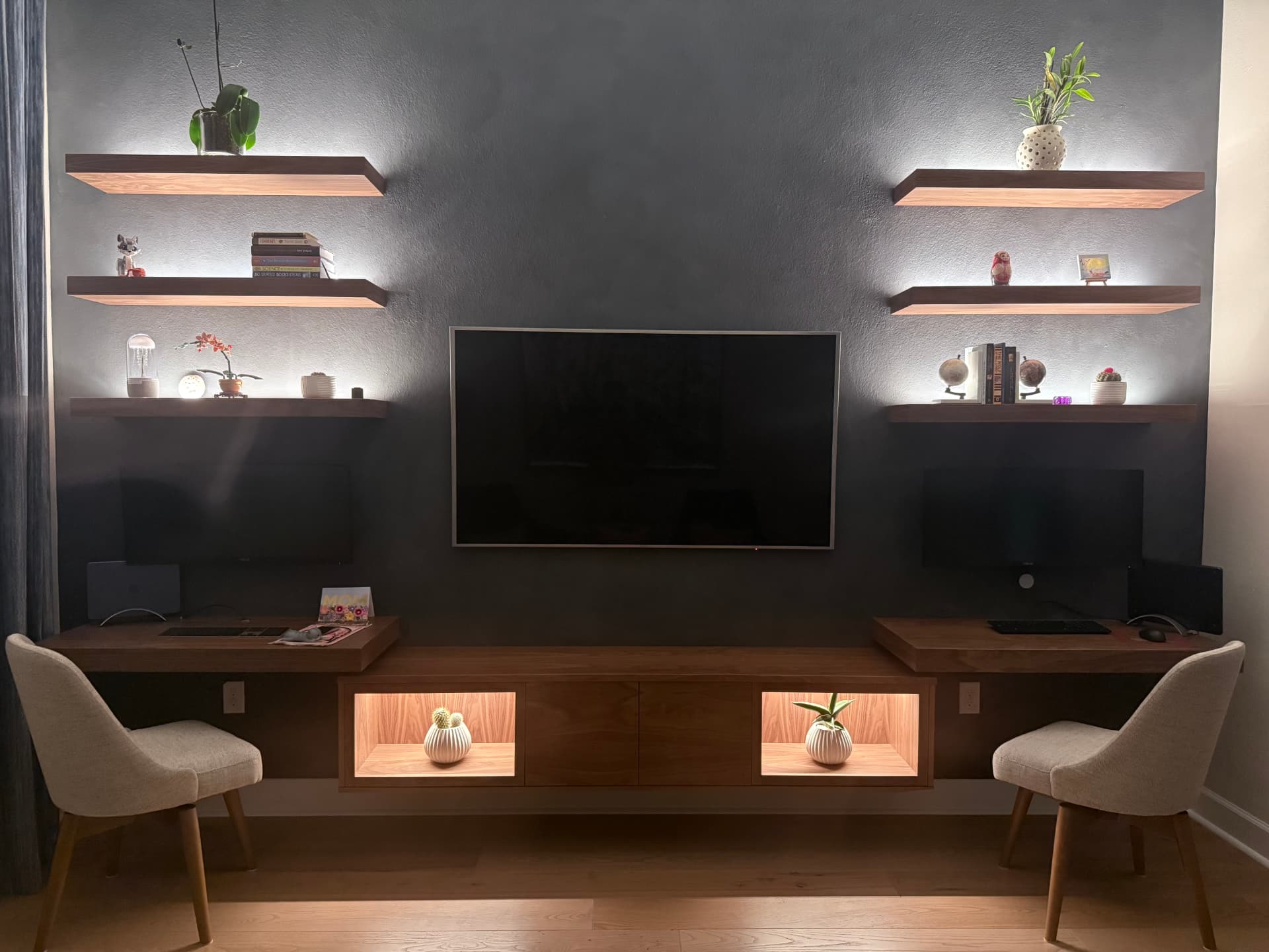 Backlit walnut floating shelves flanking a wall-mounted television